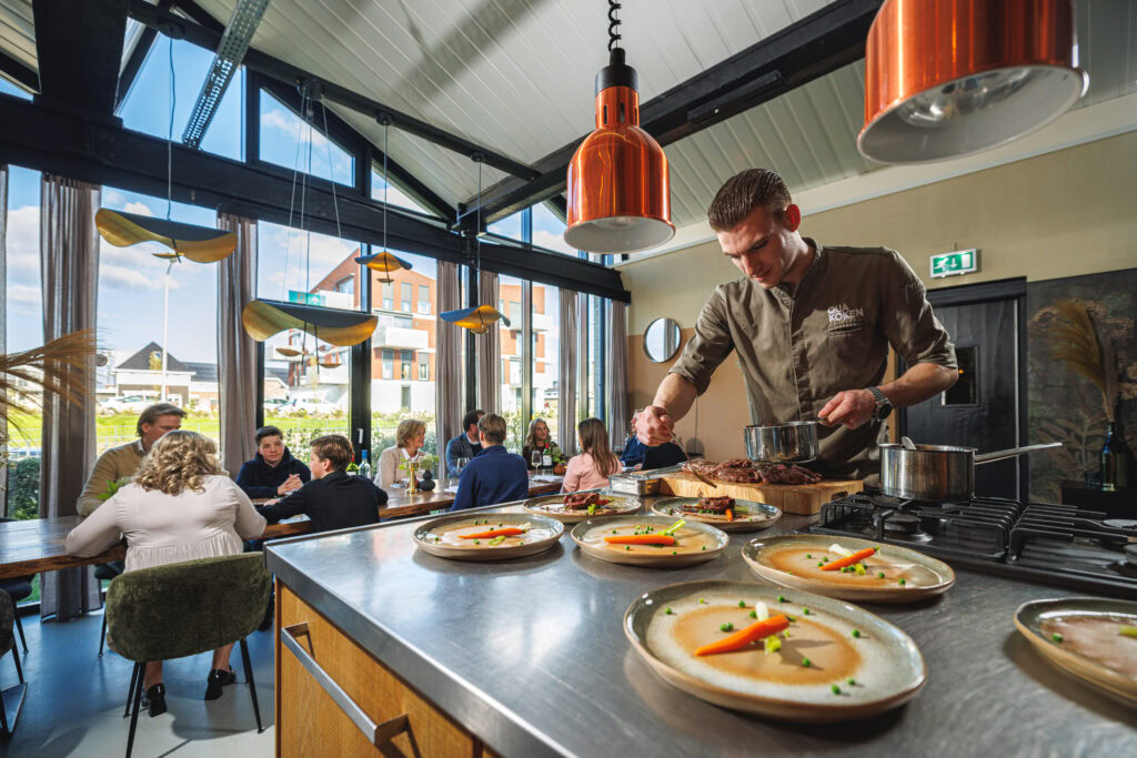 Een chef die gerechten bereidt en mensen die aan tafel zitten te eten.